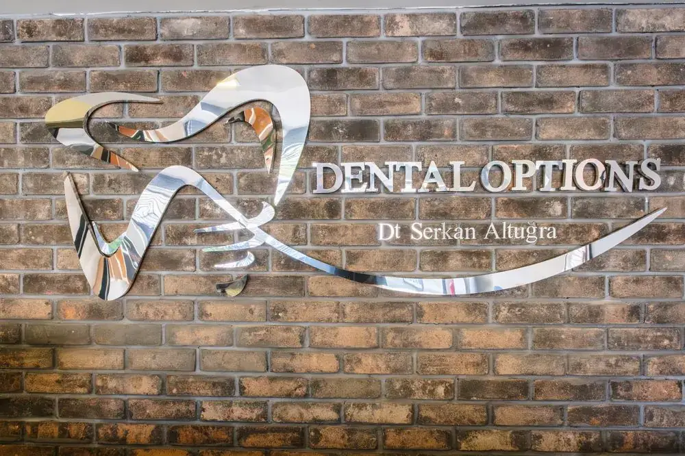 Dental Options chrome logo on brick wall